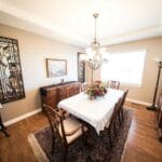 Elegancka jadalnia z drewnianym stołem, krzesłami i żyrandolem