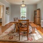 Jasna jadalnia z drewnianym stołem i krzesłami na vintage dywanie