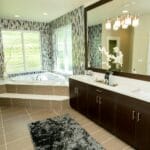 Jasna łazienka z dużym lustrem, wanną z hydromasażem i dwiema umywalkami