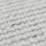 Zbliżenie na szarą, ręcznie tkaną wełnianą fakturę dywanu