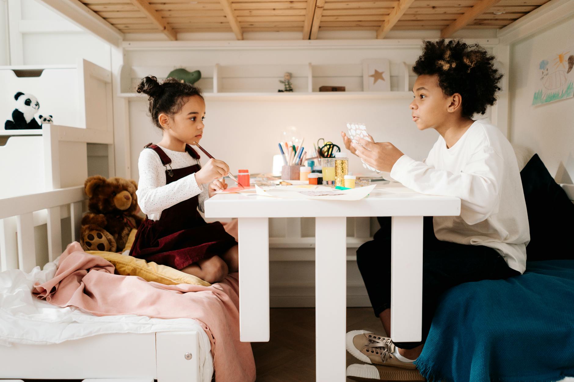 Dwoje dzieci wykonuje prace plastyczne w przytulnym pokoju dziecięcym