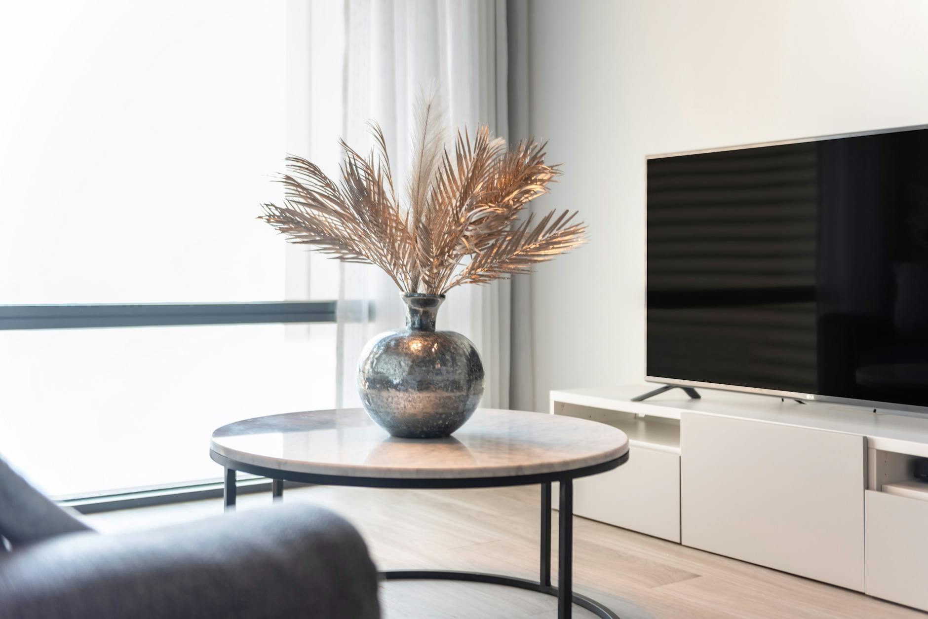 Nowoczesny salon z telewizorem, stolikiem i wazonem z liśćmi