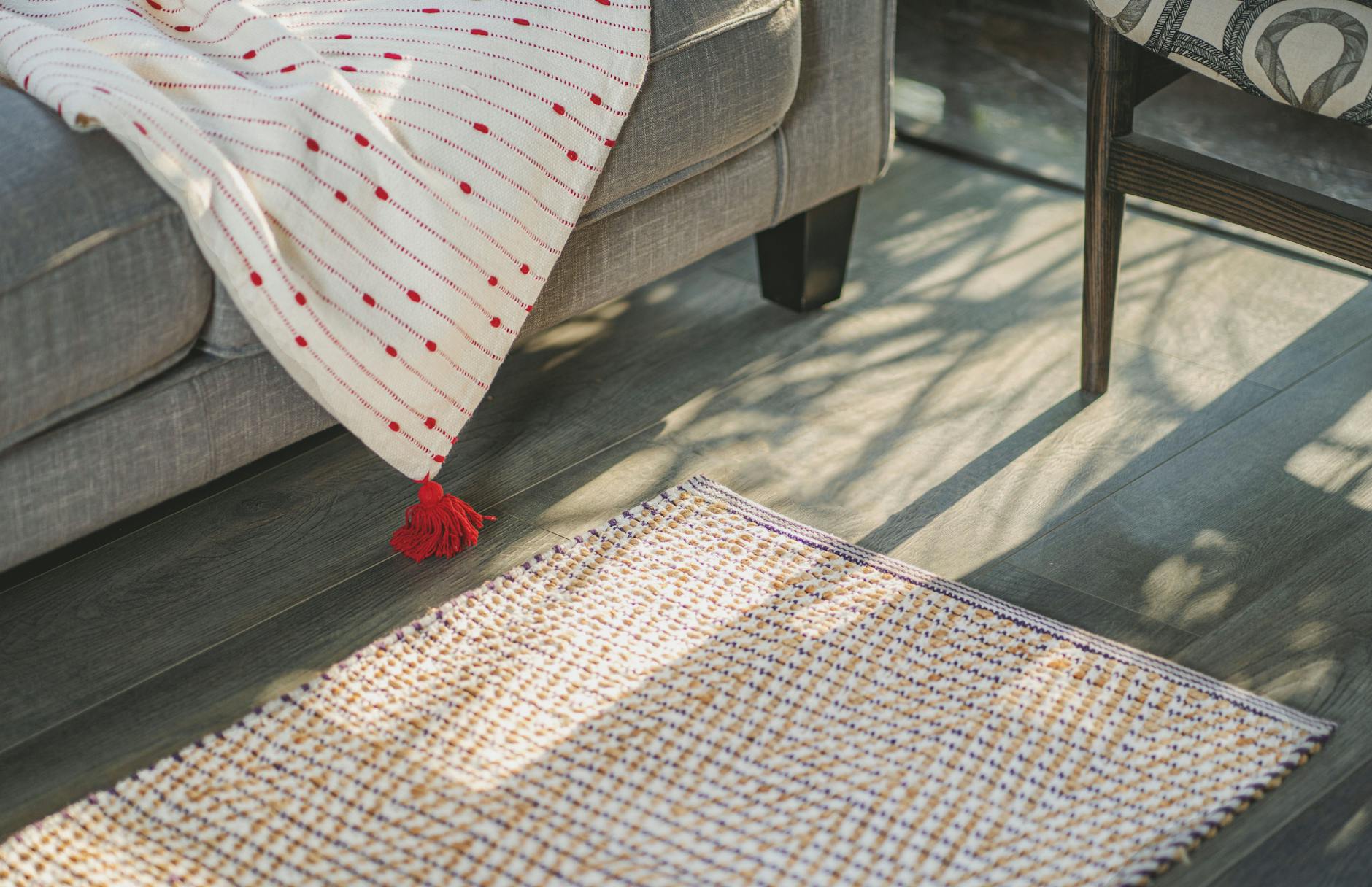 Jasny salon z szaryą sofą i teksturowanym dywanem